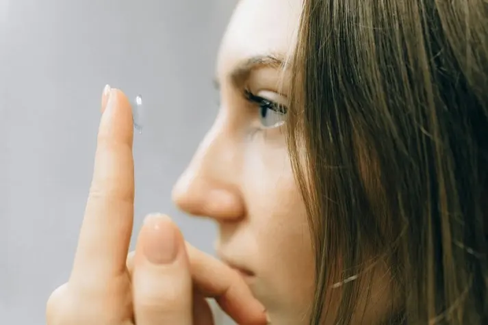 Verres - Montures - Lentilles | Jeune femme mettant une lentille de contact sur son œil.